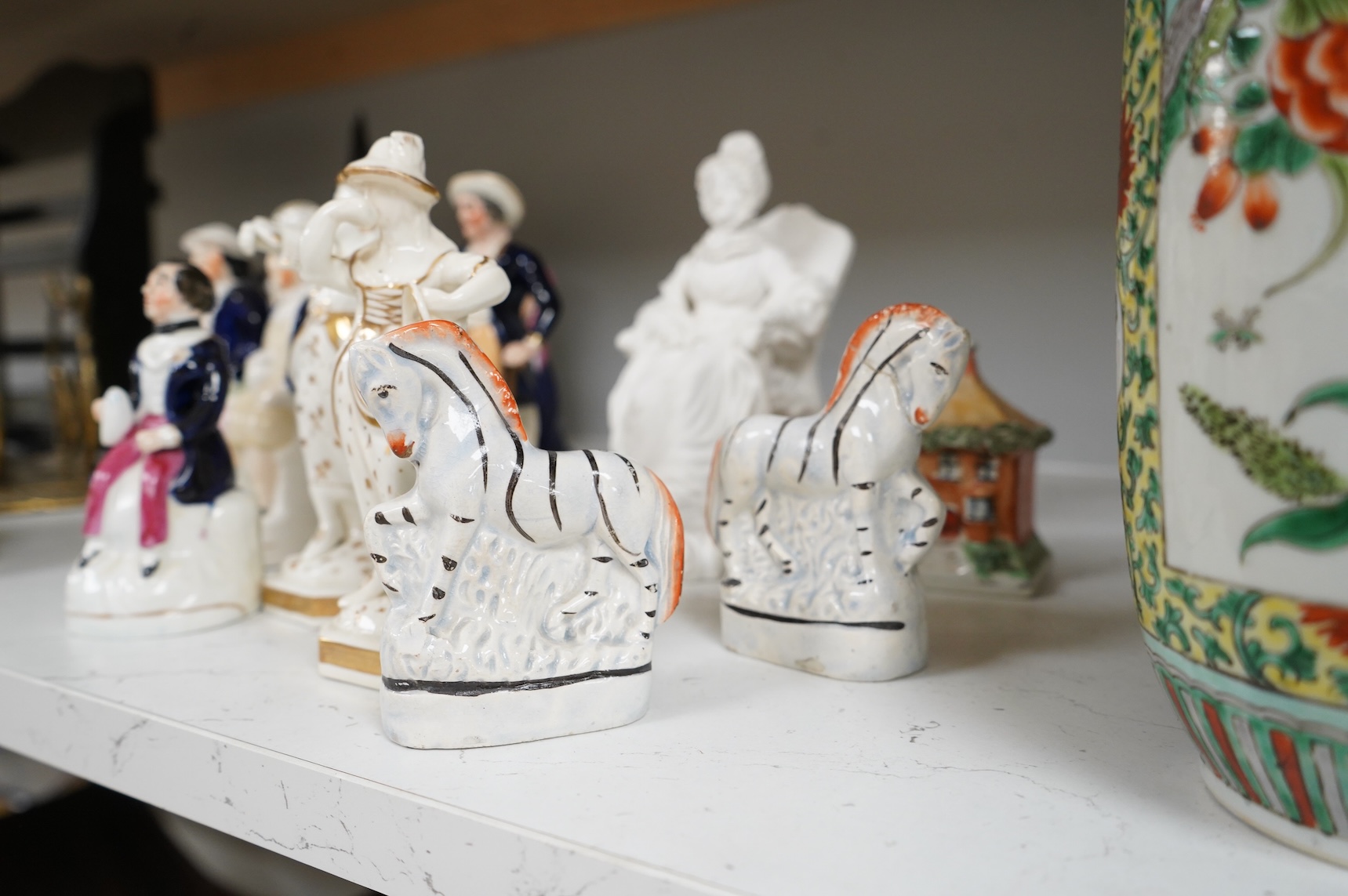 A group of mid-19th century Staffordshire porcelain figures, two models of zebras and a early 19th century Derby biscuit porcelain figure of a seated lady, largest 18cm high